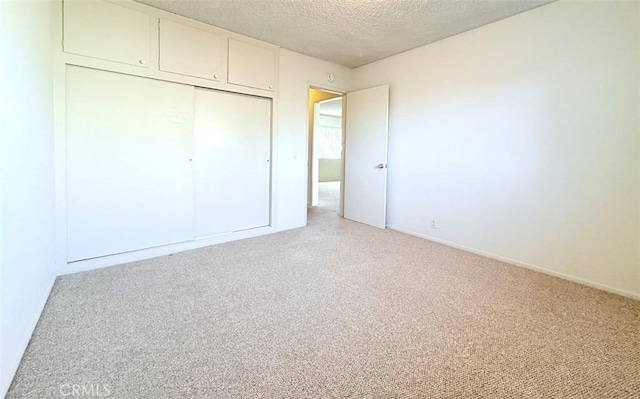 unfurnished bedroom featuring a closet, a textured ceiling, and light colored carpet