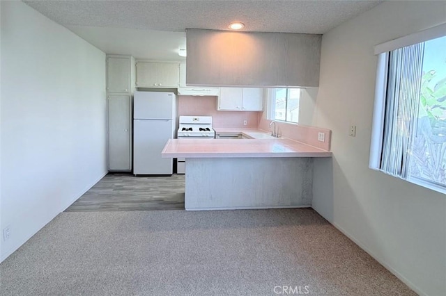 kitchen with kitchen peninsula, light carpet, custom range hood, white appliances, and sink