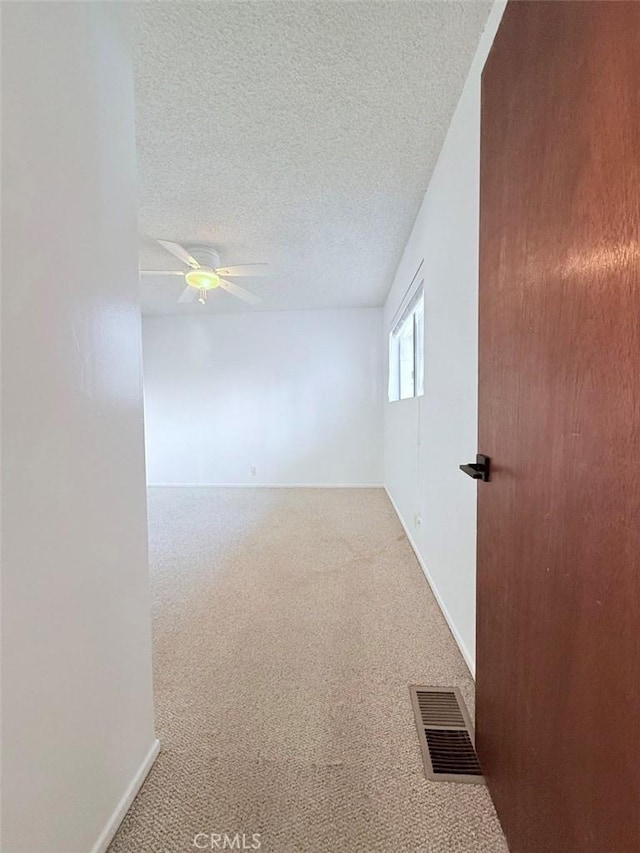 carpeted empty room featuring ceiling fan and a textured ceiling