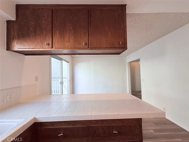 kitchen featuring tile countertops, dark brown cabinetry, and dark hardwood / wood-style floors