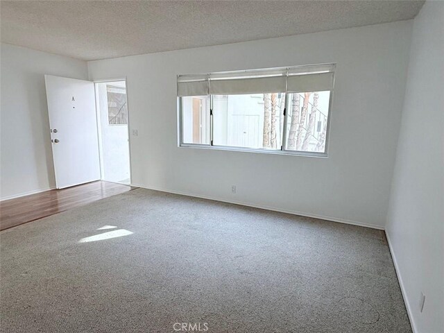 unfurnished room with carpet and a textured ceiling