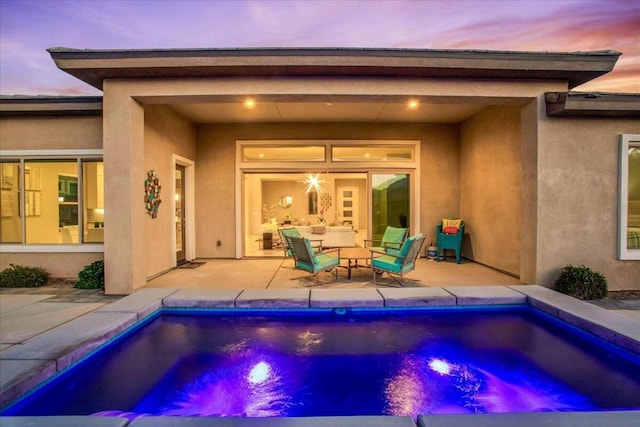 pool at dusk with outdoor lounge area and a patio area