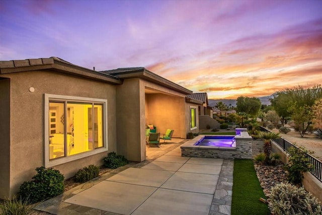 exterior space featuring an in ground hot tub and a patio area