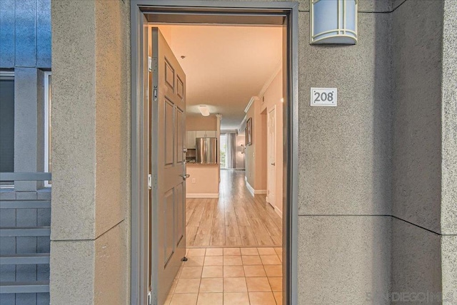 corridor with light tile patterned floors and crown molding