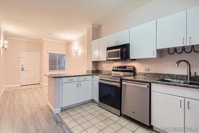 kitchen featuring kitchen peninsula, appliances with stainless steel finishes, sink, and white cabinetry