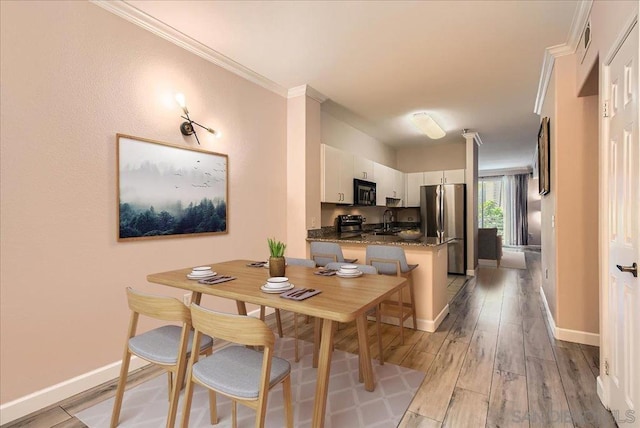 dining area with light wood-type flooring, sink, and crown molding