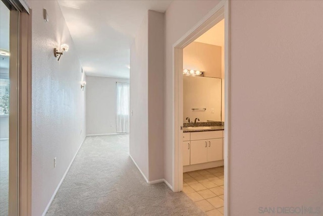 hallway with light carpet and sink