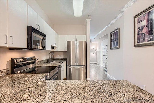 kitchen featuring stainless steel appliances, white cabinetry, dark stone counters, and sink