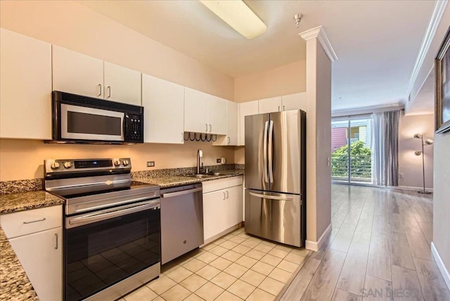 kitchen with white cabinets, stainless steel appliances, dark stone counters, sink, and crown molding