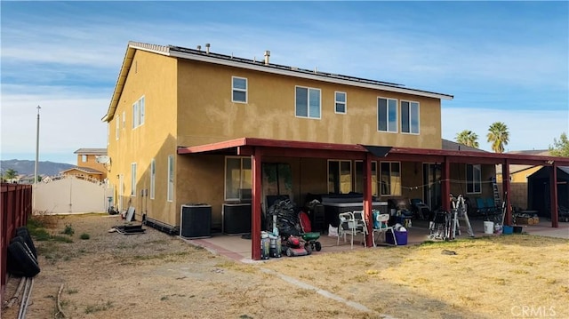 back of house with solar panels, a patio, and a hot tub