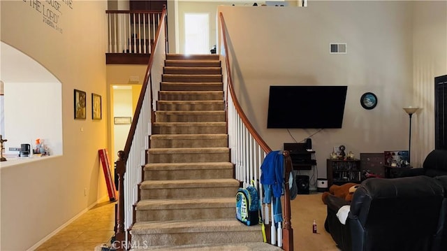 stairs featuring tile patterned flooring and a high ceiling