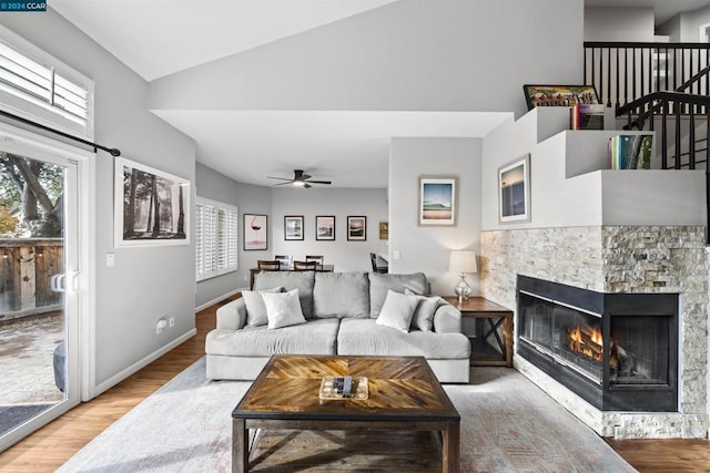 living room with ceiling fan, wood-type flooring, a fireplace, and lofted ceiling