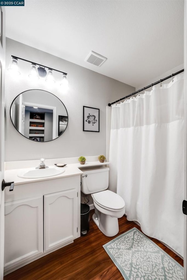 bathroom with toilet, vanity, curtained shower, and hardwood / wood-style floors