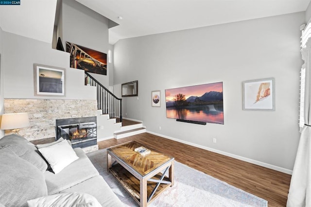 living room with wood-type flooring, a fireplace, and a towering ceiling