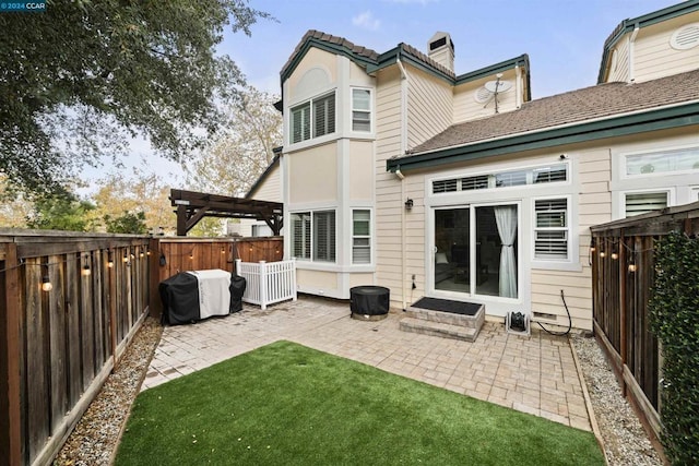 rear view of property with a pergola, a lawn, and a patio