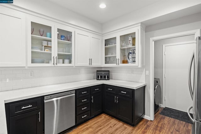 kitchen with washer / dryer, hardwood / wood-style floors, decorative backsplash, stainless steel appliances, and white cabinets