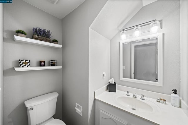 bathroom with toilet, lofted ceiling, and vanity