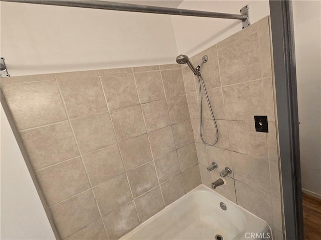 bathroom with hardwood / wood-style flooring and tiled shower / bath