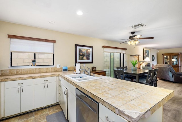 kitchen with kitchen peninsula, sink, white cabinets, and stainless steel dishwasher