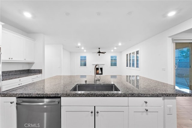 kitchen featuring white cabinetry, stainless steel dishwasher, a center island with sink, and sink