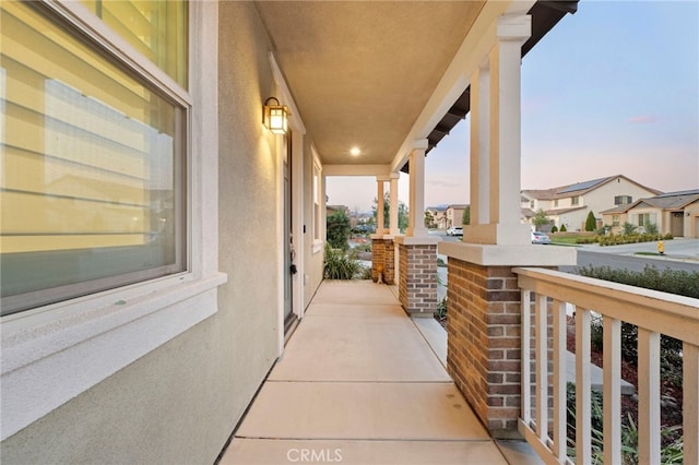 balcony at dusk featuring covered porch