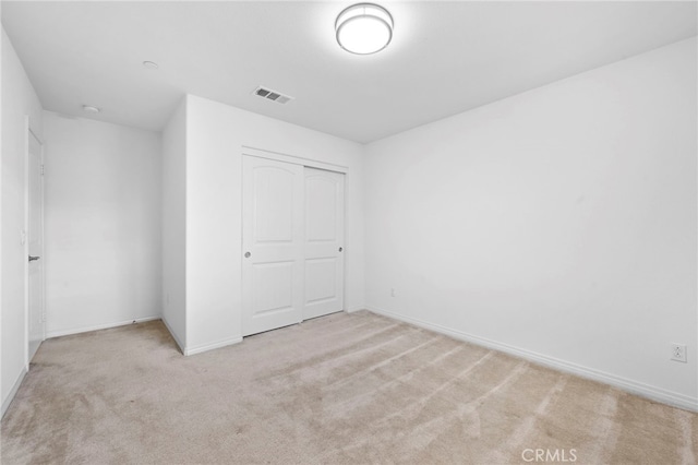 unfurnished bedroom featuring light carpet and a closet