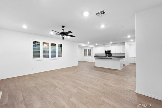 unfurnished living room with light wood-type flooring and ceiling fan