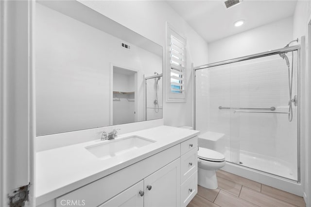 bathroom featuring hardwood / wood-style floors, vanity, toilet, and a shower with door