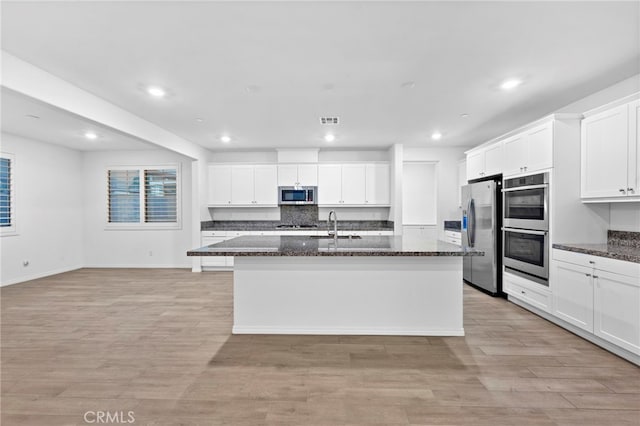 5418 Heitz Way, Fontana, CA 92336 - kitchen with stainless steel appliances, recessed lighting, a center island with sink, dark stone counters, and white cabinets