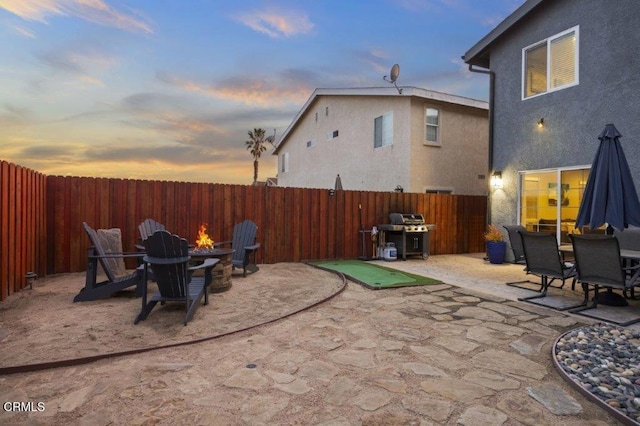 patio terrace at dusk with an outdoor fire pit and grilling area