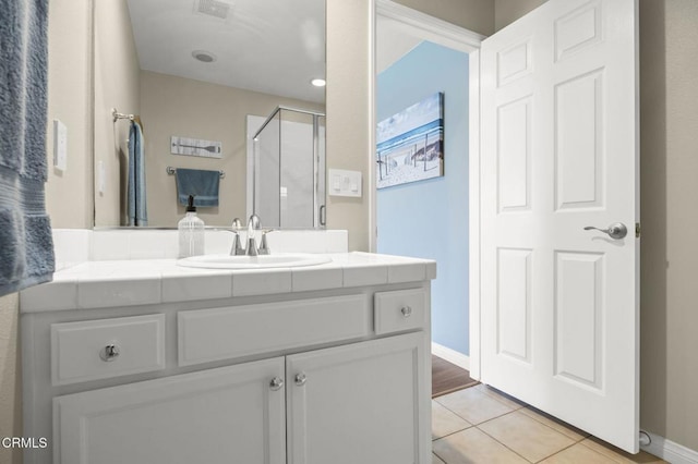 bathroom featuring a shower with shower door, vanity, and tile patterned flooring