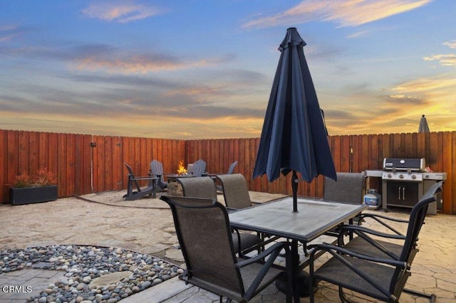 patio terrace at dusk featuring a grill