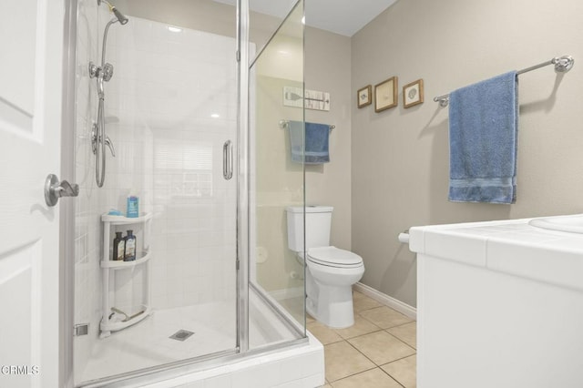 bathroom featuring tile patterned flooring, toilet, baseboards, and a stall shower