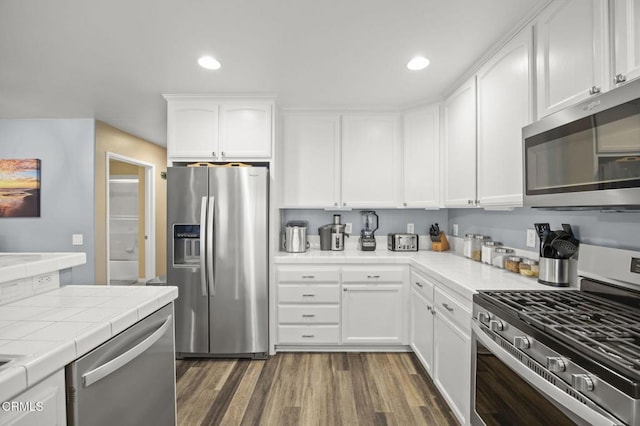 kitchen featuring dark wood-style flooring, white cabinetry, stainless steel appliances, and tile counters