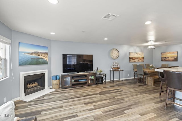 living room with visible vents, recessed lighting, a fireplace, and wood finished floors