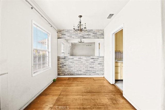 hall featuring wood-type flooring and an inviting chandelier