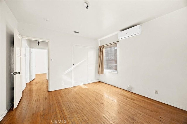 unfurnished room with light hardwood / wood-style floors and a wall mounted air conditioner