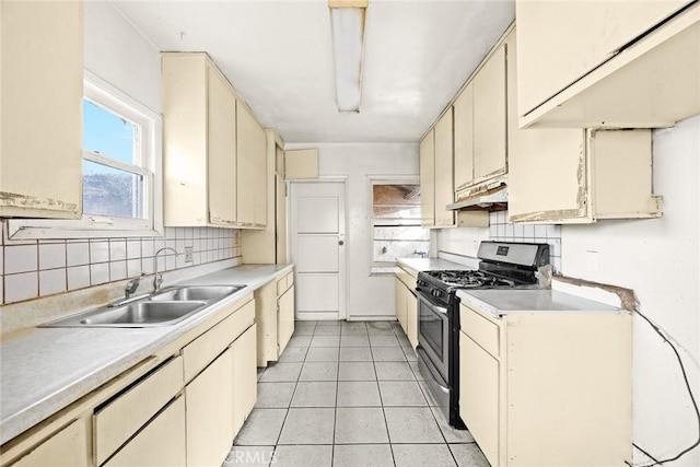 kitchen featuring stainless steel gas stove, sink, cream cabinets, decorative backsplash, and light tile patterned floors