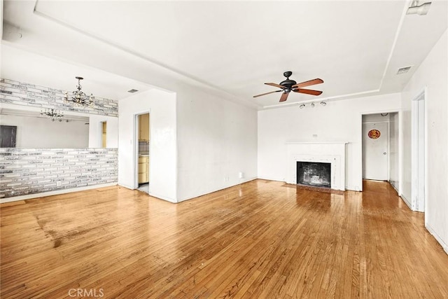 unfurnished living room with hardwood / wood-style floors and ceiling fan with notable chandelier