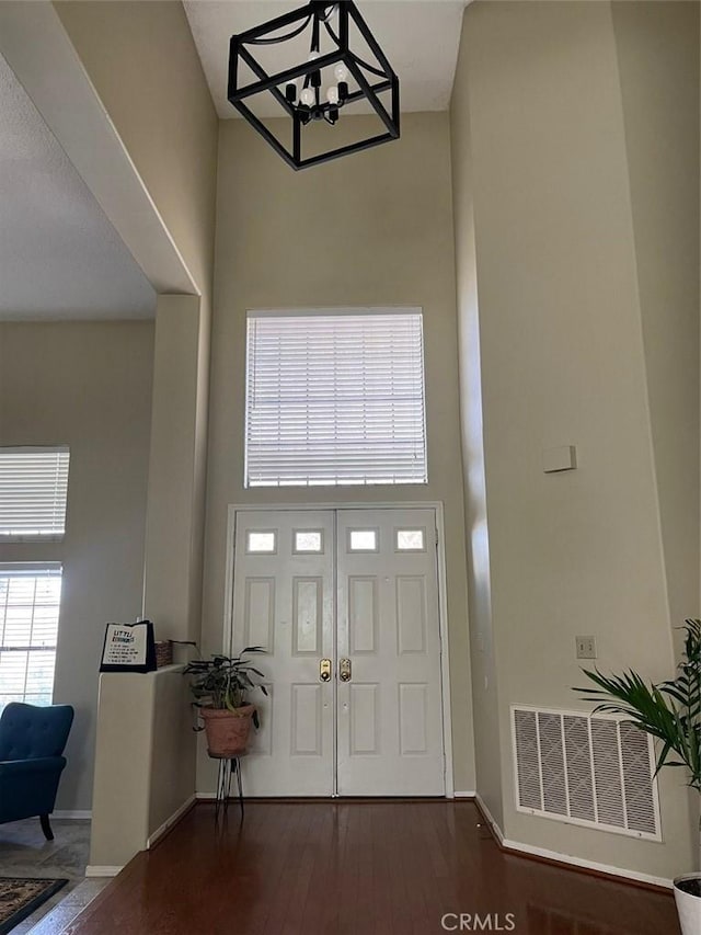 foyer entrance featuring a towering ceiling and dark hardwood / wood-style floors