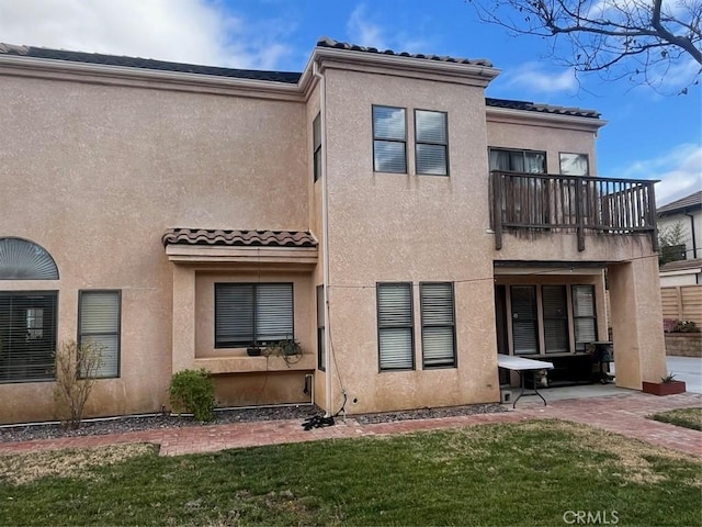 rear view of property with a lawn, a patio area, and a balcony