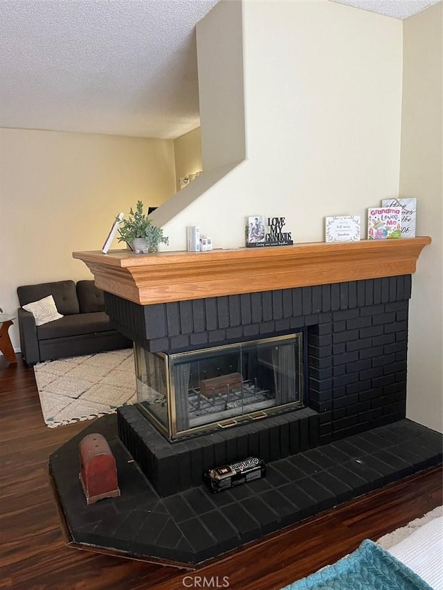 interior details with a brick fireplace, a textured ceiling, and hardwood / wood-style flooring