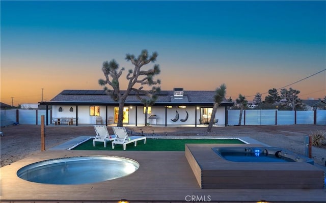 pool at dusk featuring an in ground hot tub and a patio