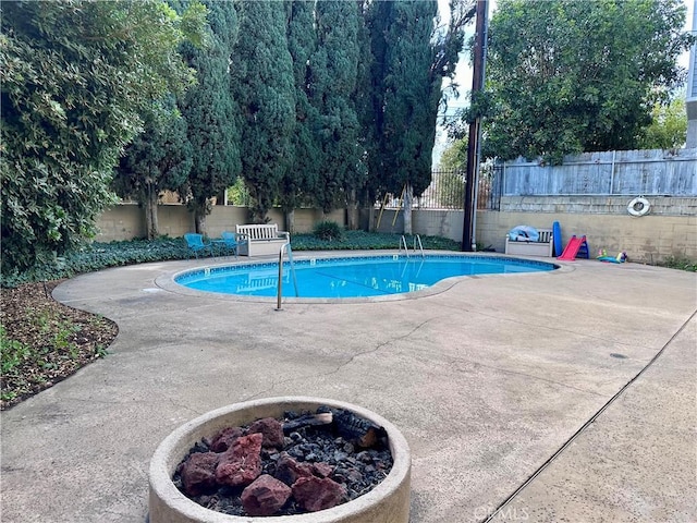 view of swimming pool with a fire pit and a patio area