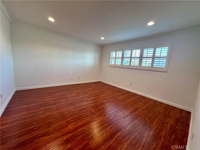 unfurnished room with ornamental molding and dark wood-type flooring