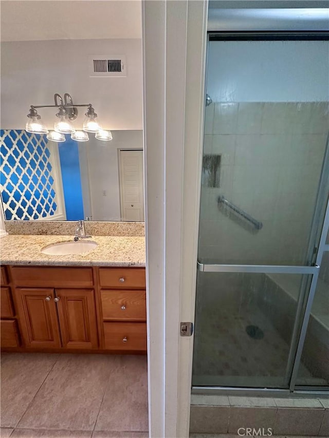 bathroom featuring tile patterned flooring, vanity, and a shower with door