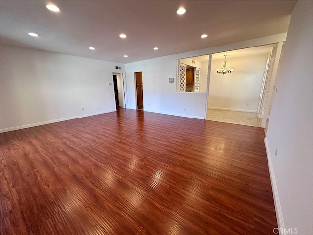 unfurnished room with wood-type flooring and a chandelier