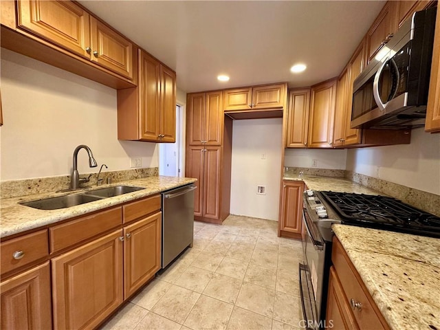 kitchen with light stone counters, appliances with stainless steel finishes, light tile patterned flooring, and sink