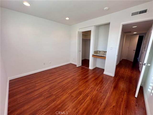 unfurnished bedroom featuring dark hardwood / wood-style flooring and a closet