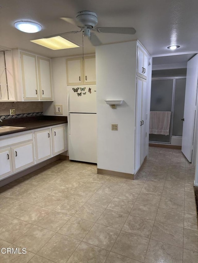 kitchen featuring white fridge, white cabinetry, ceiling fan, and sink